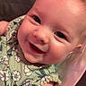baby, infant, child, smiling, happy, portrait, close_up, face, eyes, floral_clothing, green_outfit, seated, baby_seat, pink, indoor, cozy, photography, cute, joyful, head