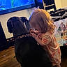 Zazu is registered to the contest to win money with this photo: toddler, dog, indoor, television, animated_character, playpen, wooden_floor, toy, child, pet, collar, furniture, polka_dot, curly_hair, interaction, family, home, candid, animation, cute