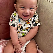 Imrane participe au concours pour gagner de l'argent avec cette photo : baby, blanket, child, clothing, couch, cute, eyebrows, fabric, face, hand, happy, head, indoor, infant, legs, mickey_mouse, person, sitting, skin, smiling