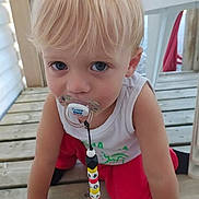 Telyo a rejoint le concours — aidez-le/la à gagner de superbes lots ! child, toddler, blonde_hair, blue_eyes, pacifier, beads, crawling, wooden_deck, white_tank_top, red_pants, outdoor, curious, baby, infant, face, person, clothing, floor, toy, closeup