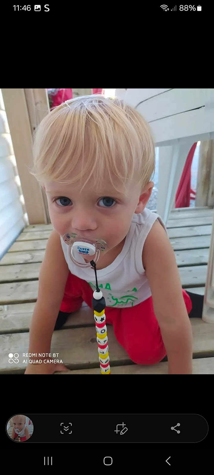 Telyo a rejoint le concours — aidez-le/la à gagner de superbes lots ! child, toddler, blonde_hair, blue_eyes, pacifier, beads, crawling, wooden_deck, white_tank_top, red_pants, outdoor, curious, baby, infant, face, person, clothing, floor, toy, closeup