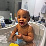 baby, bath, bathtub, water, bubbles, rubber_duck, blue_cloth, child, happy, smiling, skin, wet, indoors, toddler, person, face, sitting, cute, playful, bathroom