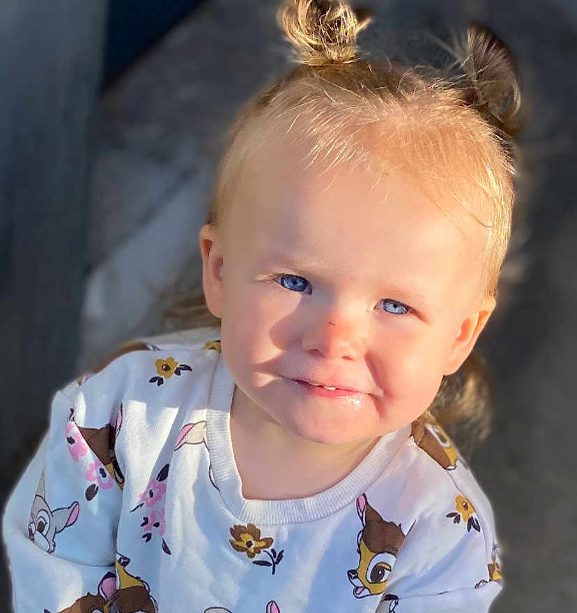 Haylona participe au concours pour gagner de l'argent avec cette photo : child, toddler, blue_eyes, smile, hair_buns, sunlight, shirt, cartoon_print, cute, portrait, outdoor, happy, face, baby, clothing, person, young_child, expression, blond_hair, casual
