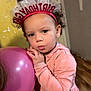 child, toddler, birthday, headband, balloon, pink, curly_hair, earrings, hoodie, indoor, wooden_floor, wall, person, clothing, cute, portrait, celebration, holding, standing, expression