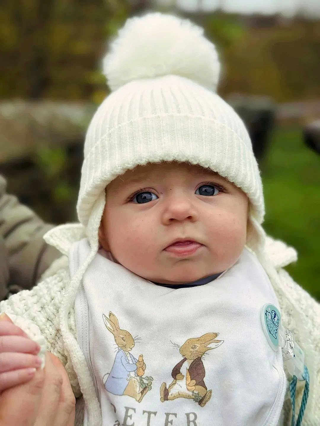 Alfie joined the competition — help win amazing prizes! baby, child, face, hat, knit_hat, pom_pom, bib, rabbit_illustration, hand, holding_hand, outdoor, portrait, cute, warm_clothing, winter, cold_weather, person, close_up, blue_eyes, soft_focus