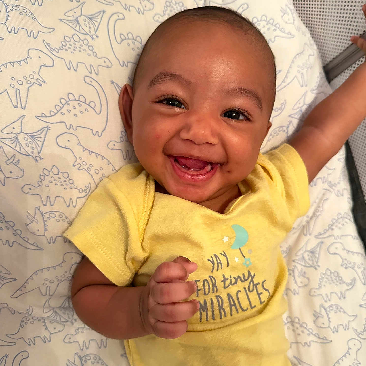 Troy joined the competition — help win amazing prizes! baby, blanket, cheerful, child, clothing, cute, dinosaur_pattern, expression, face, hand, happy, indoors, infant, lying_down, person, portrait, skin, smiling, toddler, yellow_shirt