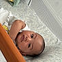 Troy is registered to the contest to win money with this photo: baby, crib, dinosaur_bedding, mesh, wooden_rail, infant, child, bed, sleeping_area, cute, resting, face, arm, white_clothing, indoor, young_child, portrait, looking_at_camera, baby_bed, toddler