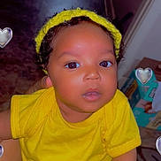 Lainey is registered to the contest to win money with this photo: baby, child, yellow_clothing, headband, indoor, person, cute, infant, skin, hand, face, eyes, curious, holding, human, portrait, young_child, heart_overlay, bright_color, floor
