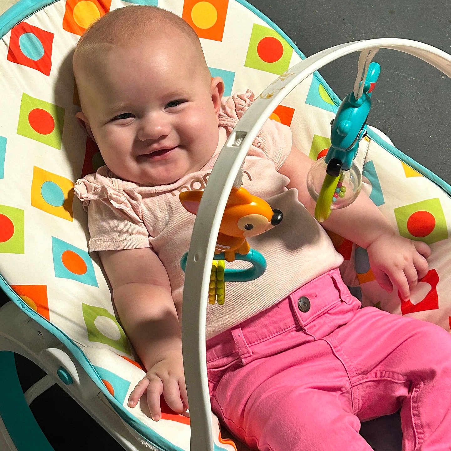 Isabella joined the competition — help win amazing prizes! baby, baby_rocker, casual, child, childhood, clothing, colorful, comfort, cute, face, happy, indoor, infant, person, pink_pants, play, relaxing, seat, smiling, toys