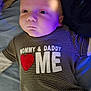 David joined the competition — help win amazing prizes! baby, infant, striped_shirt, text_on_clothing, heart_symbol, bed, blanket, blue_light, face, head, person, clothing, lying_down, indoors, cute, expressionless, young_child, portrait, soft_lighting, warm