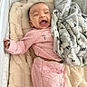 baby, infant, crib, blanket, pink_clothing, smiling, happy, soft_texture, plush, sleepwear, cozy, child, cute, lying_down, indoor, comfort, face, head, blanket_pattern, star_pattern