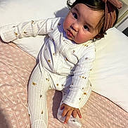 Myah joined the competition — help win amazing prizes! baby, child, infant, onesie, headband, bow, bed, pillow, blanket, pink, white, pattern, crab, starfish, cute, sitting, indoors, face, portrait, curious