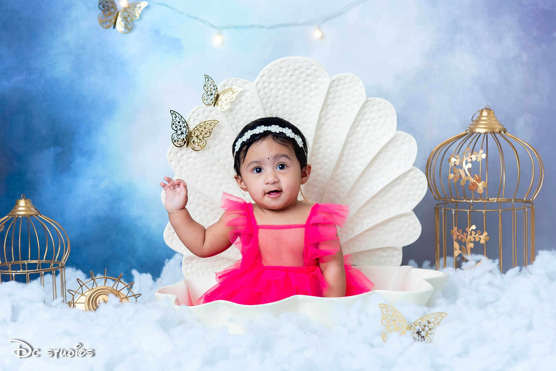 Siyara Reddy is registered to the contest to win money with this photo: baby, child, pink_dress, shell_seat, butterflies, golden_birdcage, fluffy_clouds, headband, studio_photo, portrait, smiling, decor, cute, indoor, happy, infant, face, sitting, bright_colors, whimsical