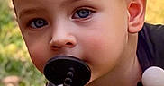 James is registered to the contest to win money with this photo: child, blonde_hair, blue_eyes, pacifier, outdoor, grass, shirt, curious, portrait, young_child, baby_accessory, cute, face, person, daylight, closeup, head, skin, expression, nature