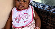 Daijah is registered to the contest to win money with this photo: baby, bib, casual_clothing, chair, child, cushion, flower_pattern, furniture, happy, headband, infant, natural_light, outdoor, pink, portrait, relaxed, seated, skin, smiling, wicker_table