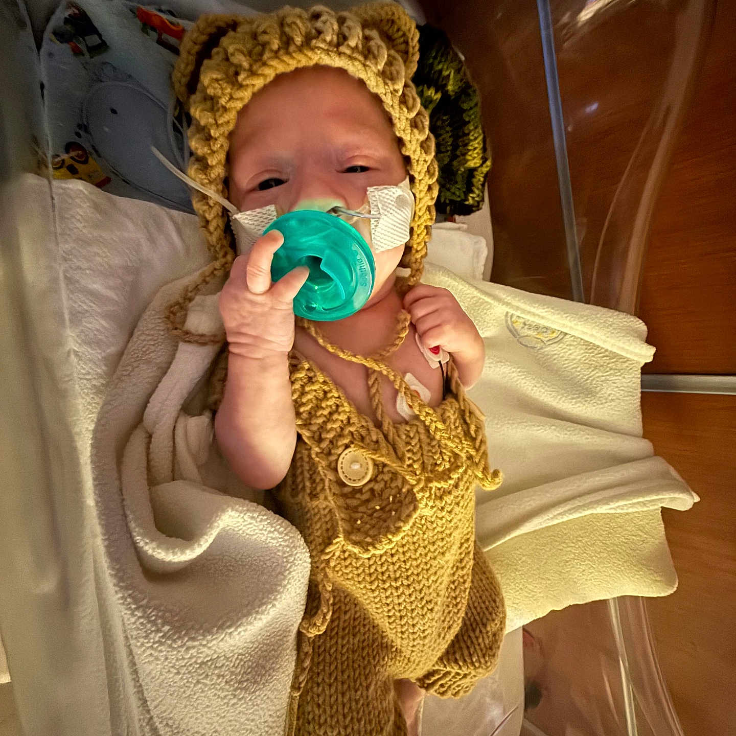 Easton is registered to the contest to win money with this photo: baby, bed, blanket, child, crib, cute, headgear, healthcare, hospital, incubator, infant, knitted_outfit, lying, medical_tubes, newborn, pacifier, person, small, wearing, wrapped