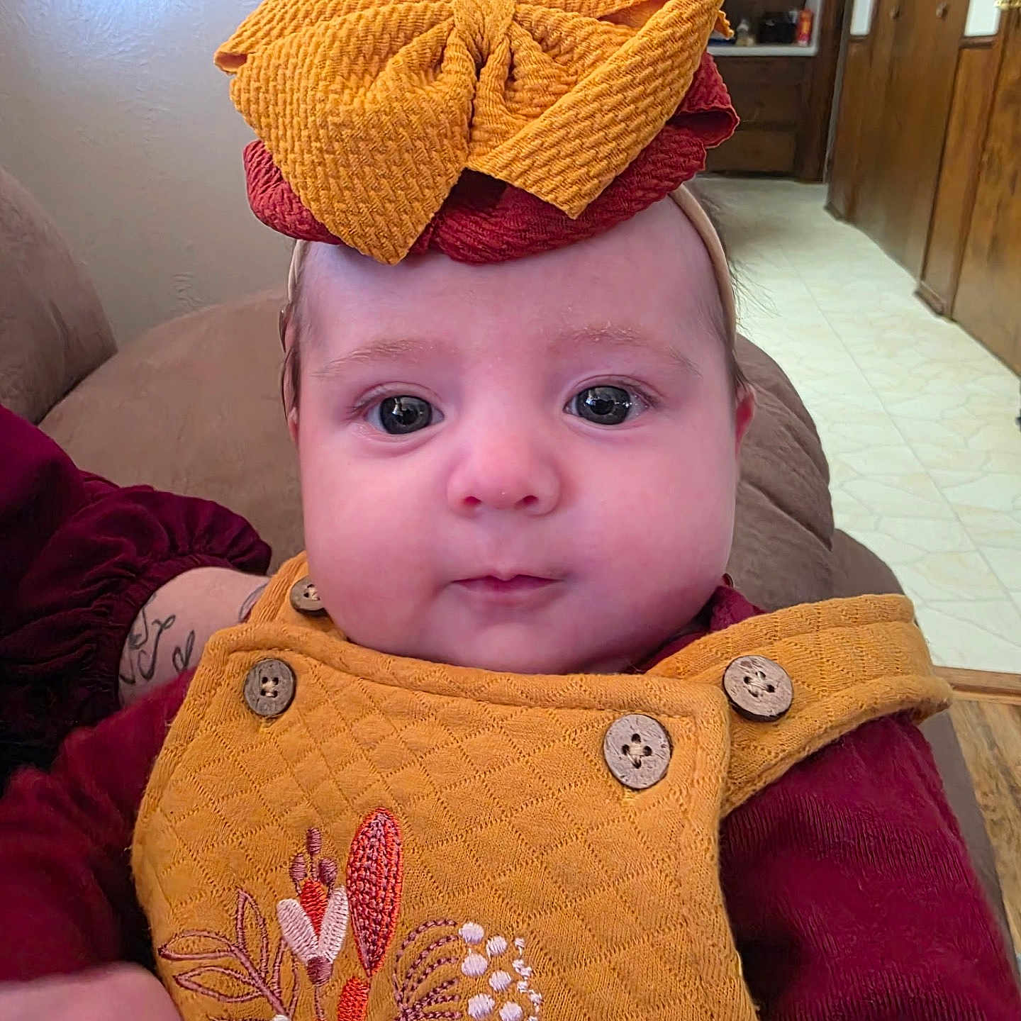 Breckilynn is registered to the contest to win money with this photo: baby, buttons, child, couch, cute, embroidered, expression, face, floor, furniture, hand, headband, indoor, infant, person, portrait, sleeves, wall, wood, yellow_clothing