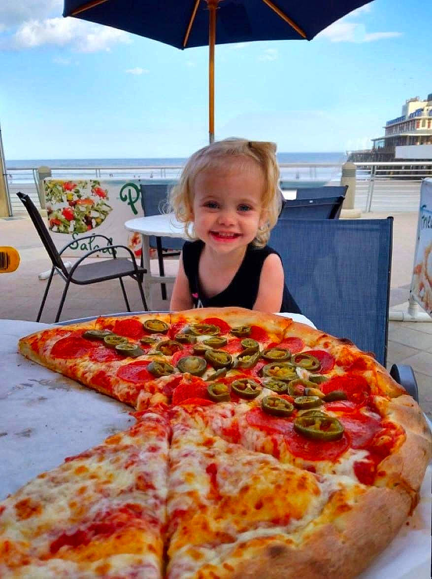 Annalise is registered to the contest to win money with this photo: california_style_pizza, chair, cheese, cloud, cooking, cuisine, dish, fast_food, food, ingredient, joy, pepperoni, person, pizza, pizza_cheese, recipe, sky, smile, summer, table