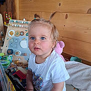 Manon a rejoint le concours — aidez-le/la à gagner de superbes lots ! baby, blue_eyes, child, colorful, curious, cute, educational_toy, furniture, indoor, person, pigtails, playroom, portrait, smiling, soft_toy, toddler, toy, white_shirt, wooden_wall, young_child