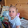 Manon a rejoint le concours — aidez-le/la à gagner de superbes lots ! baby, blue_eyes, child, colorful, curious, cute, educational_toy, furniture, indoor, person, pigtails, playroom, portrait, smiling, soft_toy, toddler, toy, white_shirt, wooden_wall, young_child