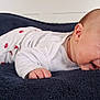 baby, bedroom, blanket, child, clothing, cozy, cute, face, happy, head, indoors, infant, lying_down, pajamas, resting, skin, sleepwear, smiling, toddler, young