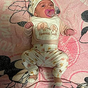 Alaina is registered to the contest to win money with this photo: baby, infant, pacifier, pajamas, hat, blanket, pink, animal_print, cute, lying_down, child, soft_texture, cartoon, comfort, sleepwear, newborn, face, small_hands, footwear, cozy