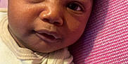 Ethan is registered to the contest to win money with this photo: baby, blanket, child, close_up, curly_hair, cute, expression, face, human, indoors, infant, lying_down, newborn, pink_blanket, portrait, skin, sleepwear, soft_light, white_clothing, young_child