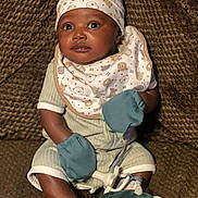 Ethan is registered to the contest to win money with this photo: baby, bib, brown, clothing, couch, cozy, cute, expression, face, footwear, hat, indoor, infant, mittens, person, plush, sitting, soft, textile, young_child