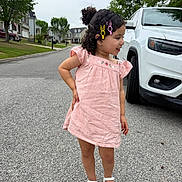 Kaleah joined the competition — help win amazing prizes! child, girl, pink_dress, hair_clips, sandals, street, suburban, car, white_suv, trees, sidewalk, curb, grass, residential_area, smiling, hair, outdoor, summer, playful, pose