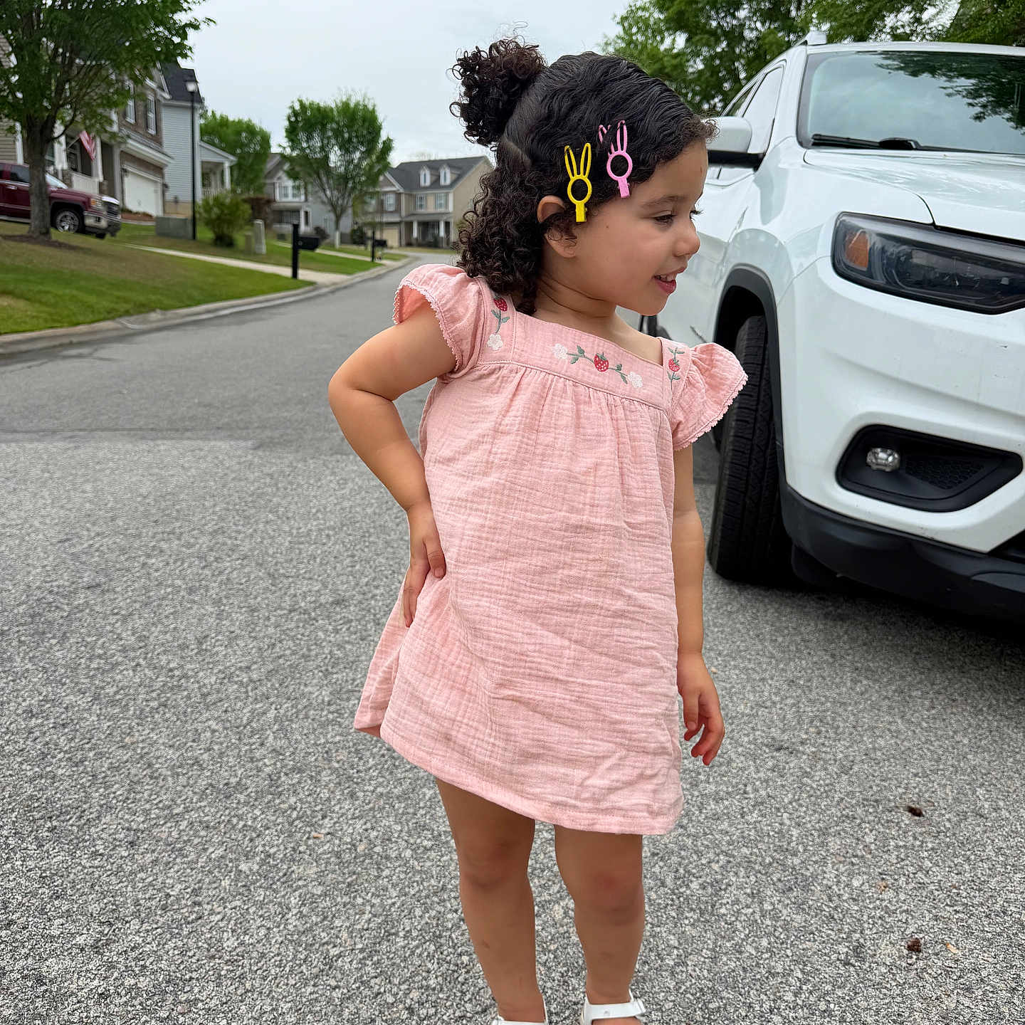 Kaleah joined the competition — help win amazing prizes! child, girl, pink_dress, hair_clips, sandals, street, suburban, car, white_suv, trees, sidewalk, curb, grass, residential_area, smiling, hair, outdoor, summer, playful, pose