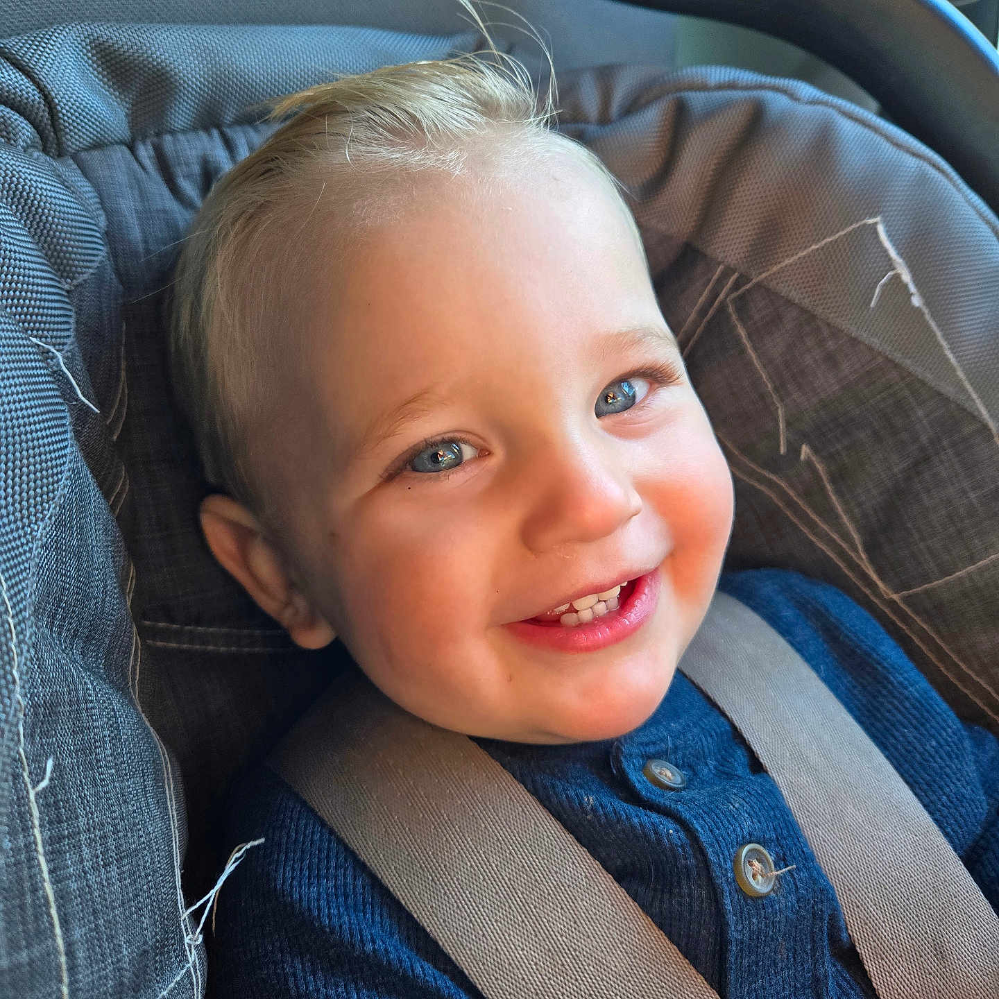 Shiloh is registered to the contest to win money with this photo: accessories, baby, belt, car, car_interior, clothing, coat, cushion, face, happy, head, homedecor, pants, person, photography, portrait, seatbelt, smile, transportation, vehicle