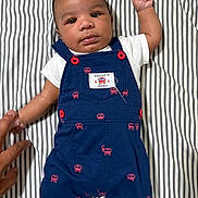 Yosiah joined the competition — help win amazing prizes! baby, infant, child, striped_sheet, blue_romper, red_buttons, red_bus_prints, white_shirt, white_socks, hand, finger_hold, lying_down, portrait, cute, curious, indoors, bed, fabric, person, newborn