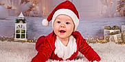 Lynaé participe au concours pour gagner de l'argent avec cette photo : baby, celebration, child, christmas, cute, decorations, face, festive, gifts, happy, holiday, indoor, lantern, lights, portrait, red_clothing, santa_hat, seasonal, smiling, white_rug