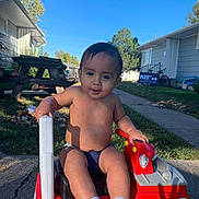 Trevon Gibbons Jr joined the competition — help win amazing prizes! toddler, child, toy, fire_truck, outdoor, sunny, smiling, socks, sidewalk, grass, picnic_table, house, daytime, play, person, cute, shirtless, vehicle, young_child, parked_toy