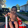 toddler, child, toy, fire_truck, outdoor, sunny, smiling, socks, sidewalk, grass, picnic_table, house, daytime, play, person, cute, shirtless, vehicle, young_child, parked_toy
