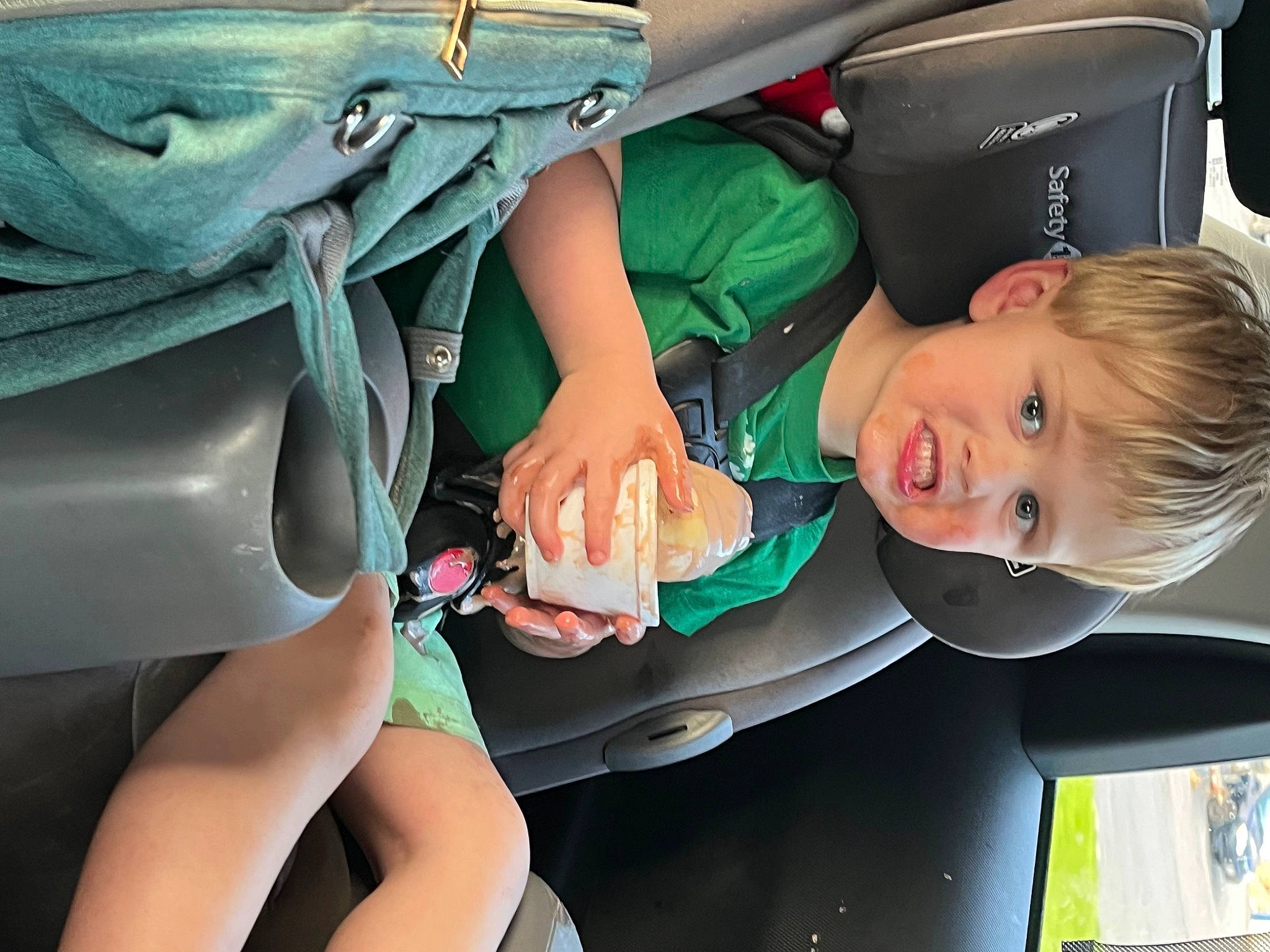Oliver is registered to the contest to win money with this photo: auto_part, baby_products, child, comfort, fashion_accessory, fun, glove, grass, green, human_leg, joint, leisure, medical_procedure, mouth, nail, person, service, sitting, smile, toddler
