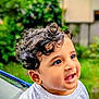 baby, background_blur, child, curly_hair, cute, daylight, expression, face, greenery, hand, happy, indian_flag, nature, outdoor, person, portrait, skin, smiling, toddler, white_shirt