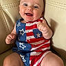 baby, infant, smile, happy, romper, clothing, pattern, stars, stripes, red, white, blue, skin, face, arm, leg, seated, chair, leather, cute