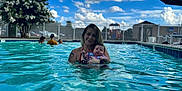 Ariya is registered to the contest to win money with this photo: woman, baby, pool, water, swimming, sky, clouds, outdoor, fence, people, summer, relaxation, family, swimsuit, playground, umbrella, daylight, nature, recreation, leisure