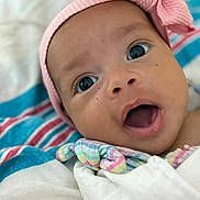 Melani Rodriguez is registered to the contest to win money with this photo: baby, infant, face, headband, pink_bow, wide_eyes, wrapped, blanket, colorful, striped, closeup, expression, cute, soft, skin, mouth_open, portrait, child, newborn, indoors