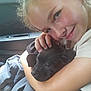 Ziggy Stardust joined the competition — help win amazing prizes! child, girl, puppy, dog, pet, cuddle, smile, car_interior, seat, clothing, hand, face, young, happy, closeup, animal, friendship, affection, black_dog, casual