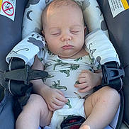 Lincoln is registered to the contest to win money with this photo: baby, sleeping, car_seat, onesie, dinosaur_pattern, infant, child, straps, warning_label, cute, peaceful, foot, hand, paciifier, seatbelt, rest, young, infancy, safety, comfort