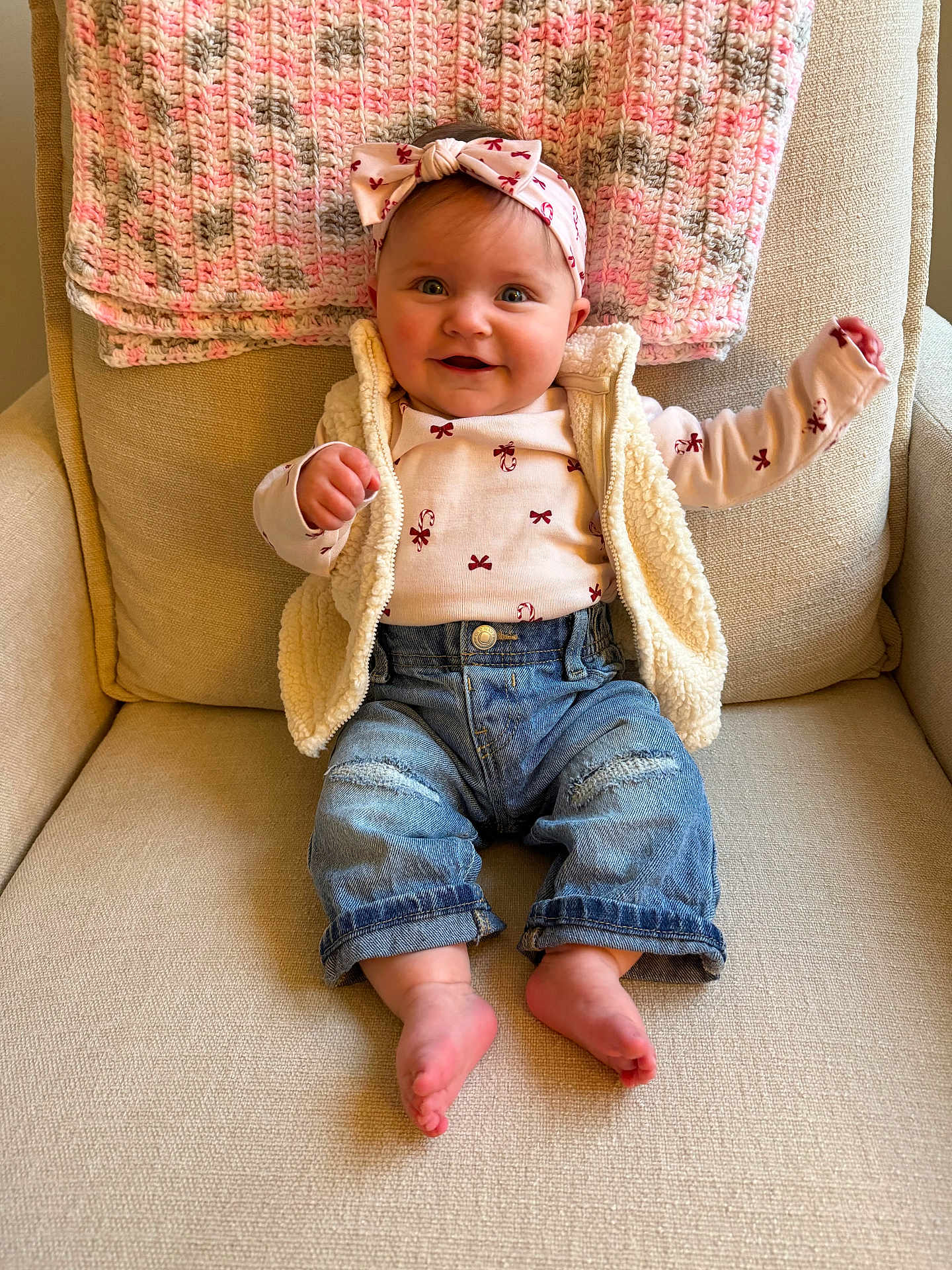 Leighton Shaw joined the competition — help win amazing prizes! baby, child, smiling, headband, bow, knitted_blanket, armchair, denim_jeans, vest, long_sleeve_shirt, barefoot, indoor, cute, happy, portrait, infant, seated, cozy, warm_colors, comfortable