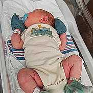 Jasper is registered to the contest to win money with this photo: baby, bassinet, bed, blanket, booties, child, clothing, cute, dinosaur, healthcare, hospital, hospital_id, infant, mittens, newborn, onesie, pacifier, patient, resting, sleeping