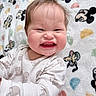 baby, child, face, expression, scrunched_face, onesie, animal_print, blanket, mickey_mouse, pattern, cute, funny, infant, smile, chubby_cheeks, lying_down, indoors, soft_toy_pattern, happy, person