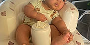 Mateo is registered to the contest to win money with this photo: baby, infant, child, inflatable_chair, teddy_bear_pattern, indoor, living_room, couch, window, daylight, curious_expression, barefoot, onesie, soft_lighting, cozy, furniture, person, seat, foot, head