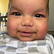 Mateo joined the competition — help win amazing prizes! baby, child, face, smile, cheeks, eyes, clothing, pattern, indoor, portrait, closeup, happy, infant, person, cute, skin, head, young, expression, sitting