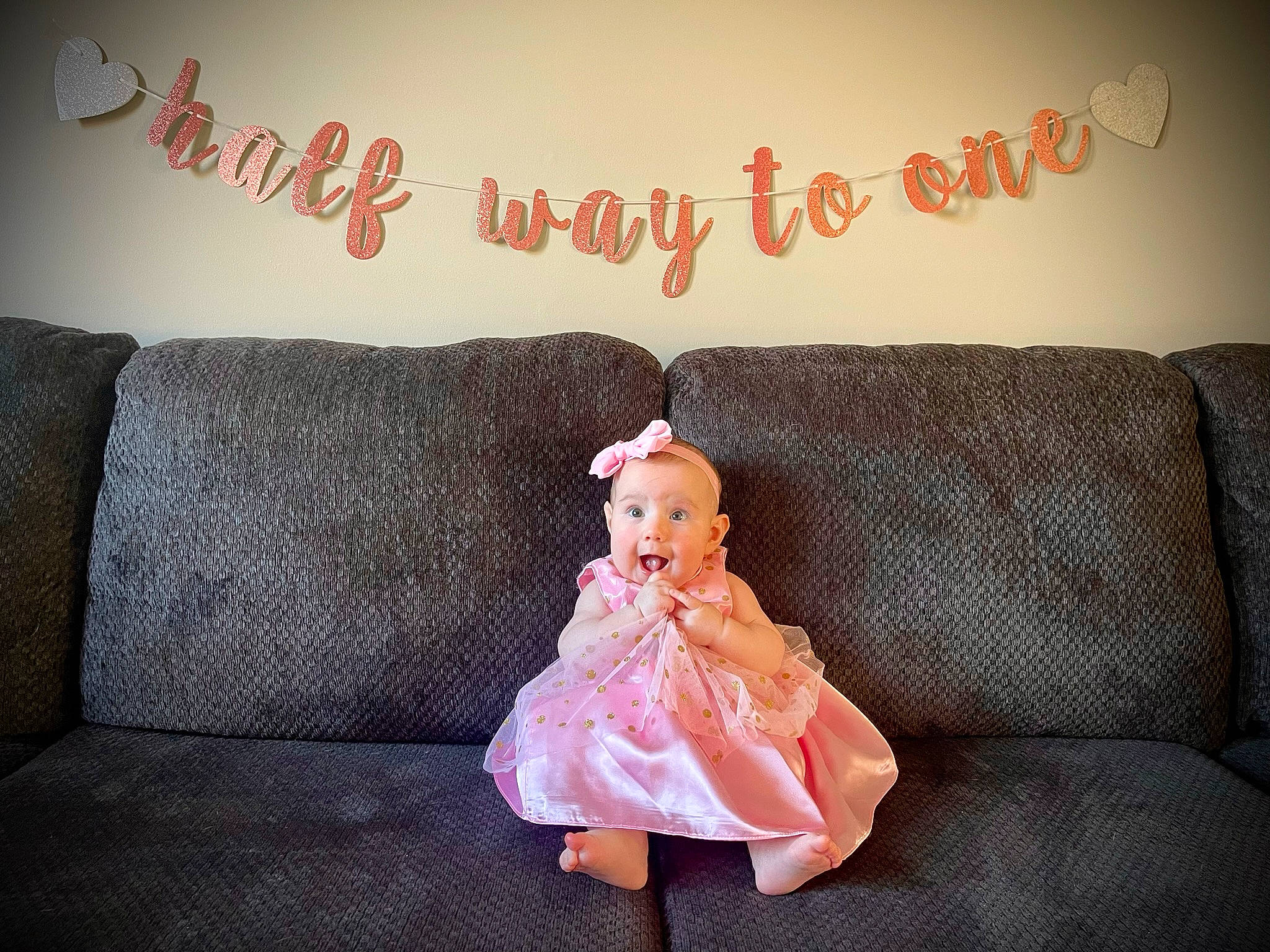 Mckenna is registered to the contest to win money with this photo: comfort, couch, doll, dress, event, flooring, font, leg, linens, living_room, magenta, ornament, pattern, person, pillow, pink, room, sitting, textile, throw_pillow