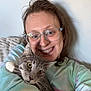 Pip joined the competition — help win amazing prizes! casual, cat, close_up, couch, eyes, face, feline, fur, glasses, gray_cat, happy, hugging, indoor, person, smile, sweatshirt, tabby_cat, tie_dye, wall, whiskers