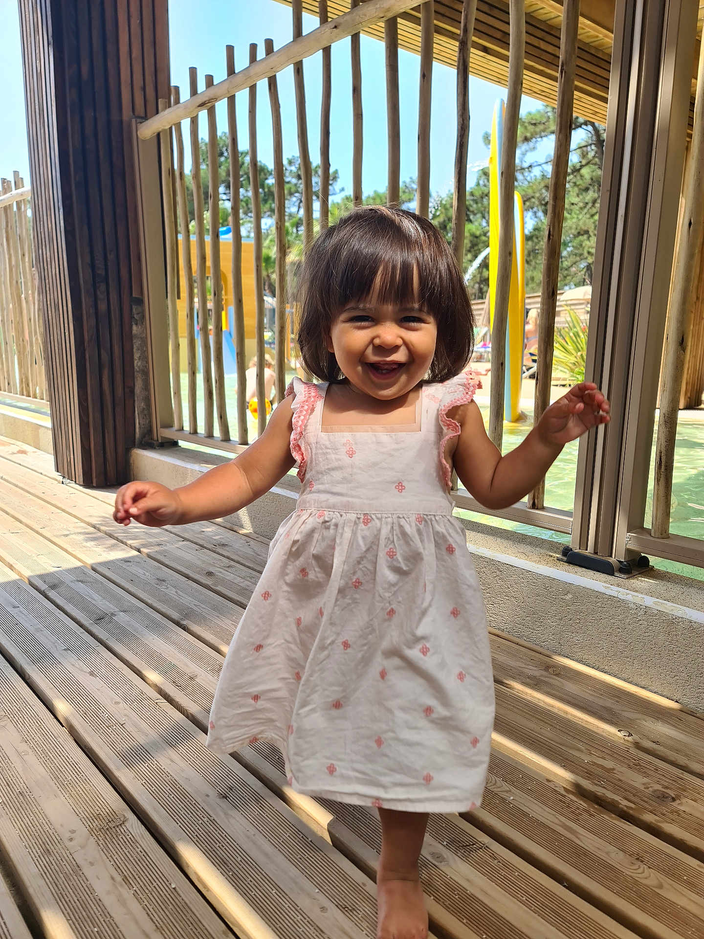 Lilas participe au concours pour gagner de l'argent avec cette photo : toddler, child, smiling, dress, barefoot, wooden_floor, outdoor, sunlight, railing, happy, girl, daylight, nature, person, playground, summer, cute, young_child, portrait, walking